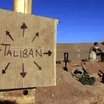Marines estadounidenses llenan sacos de arena cerca de un letrero de cartón que recuerda a todos que las fuerzas talibanes podrían estar en cualquier lugar, en el sur de Afganistán el 1 de diciembre de 2001