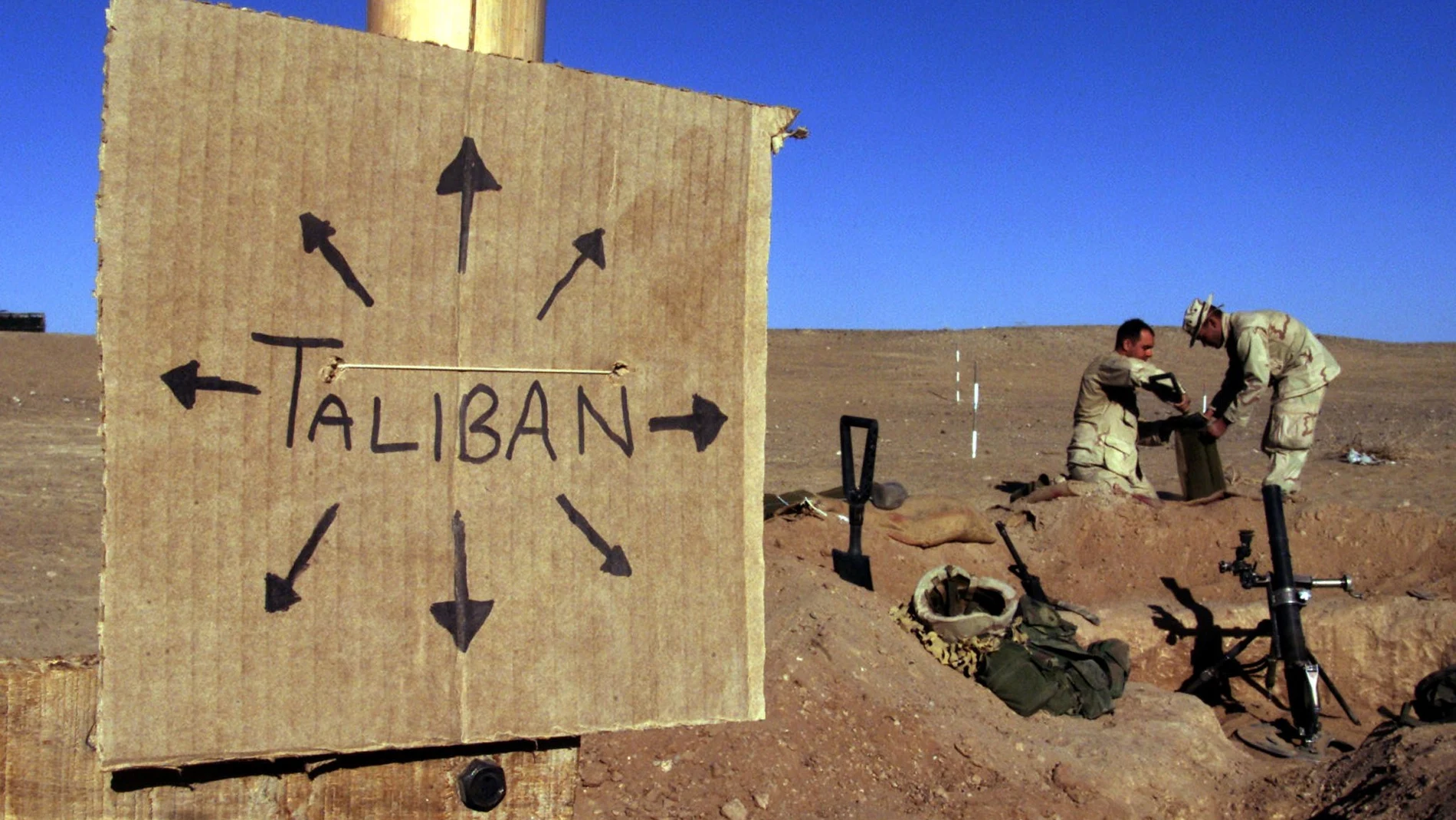 Marines estadounidenses llenan sacos de arena cerca de un letrero de cartón que recuerda a todos que las fuerzas talibanes podrían estar en cualquier lugar, en el sur de Afganistán el 1 de diciembre de 2001