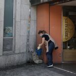 Una señora utiliza agua de una fuente para limpiar en el distrito de Puente de Vallecas, Madrid (España)