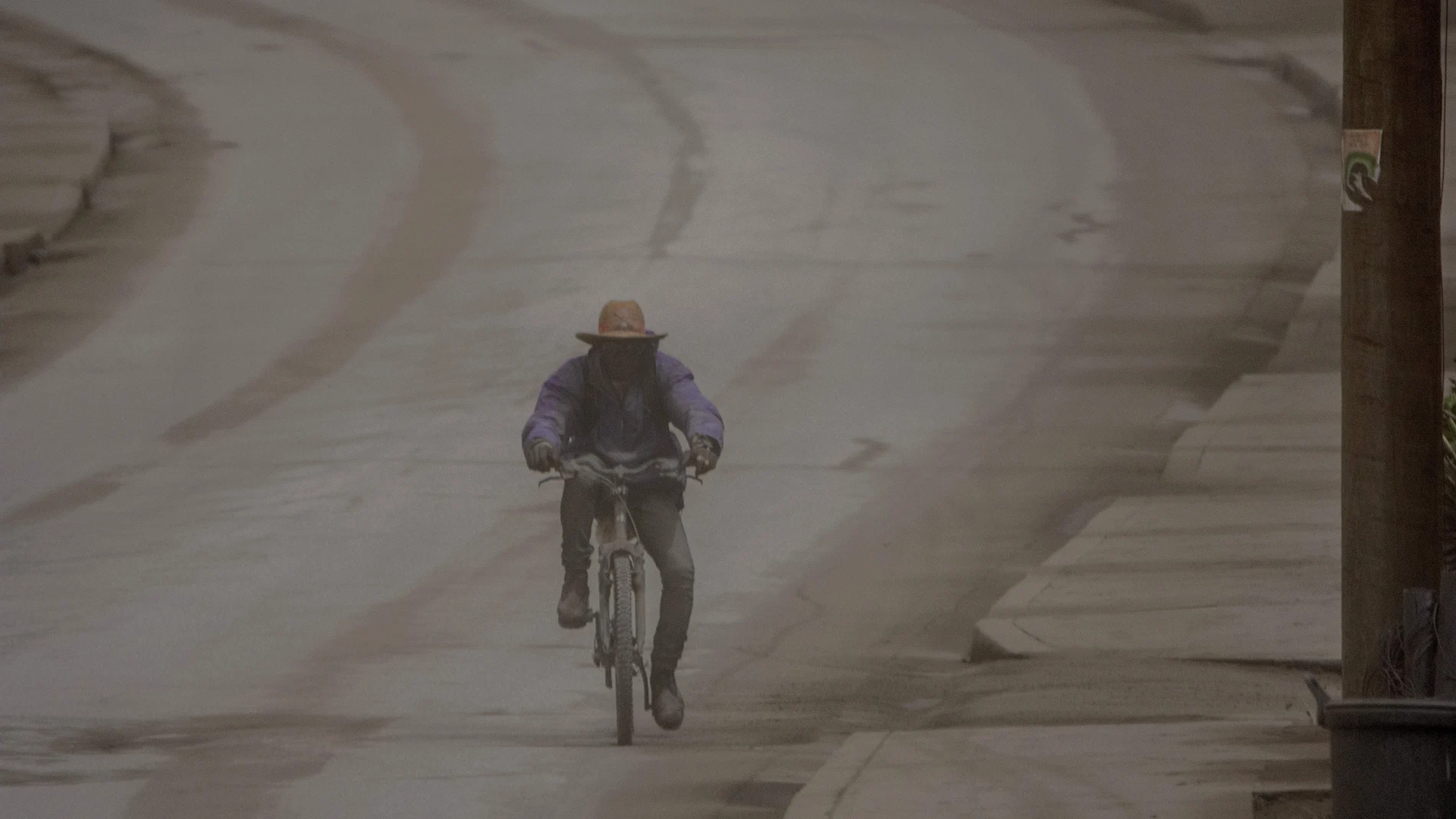 Un hombre circula con su bicicleta entre una nube de cenizas provocada por el volcán La Soufriere