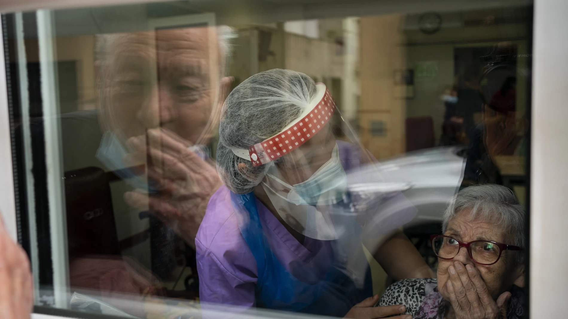 Javier Anto besa a su esposa, Carmen Panzano, a través del cristal de la residencia de Barcelona en la que ella vive