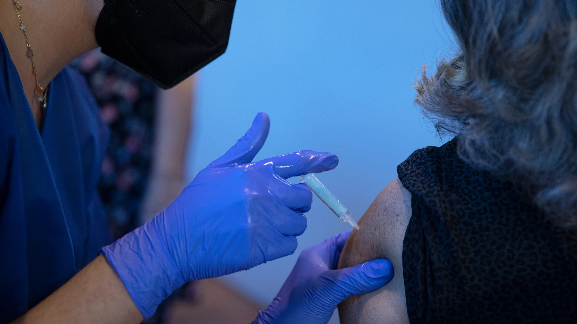 Una sanitaria vacuna a una mujer en la primera jornada de vacunación ante la Covid-19 en el Estadio de La Cartuja de Sevilla