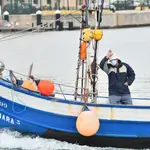 Un hombre saluda al mismo tiempo en que Agentes de Salvamento Marítimo de la Guardia Civil detienen a varios pesqueros marroquíes, a 22 de abril de 2021, en Ceuta