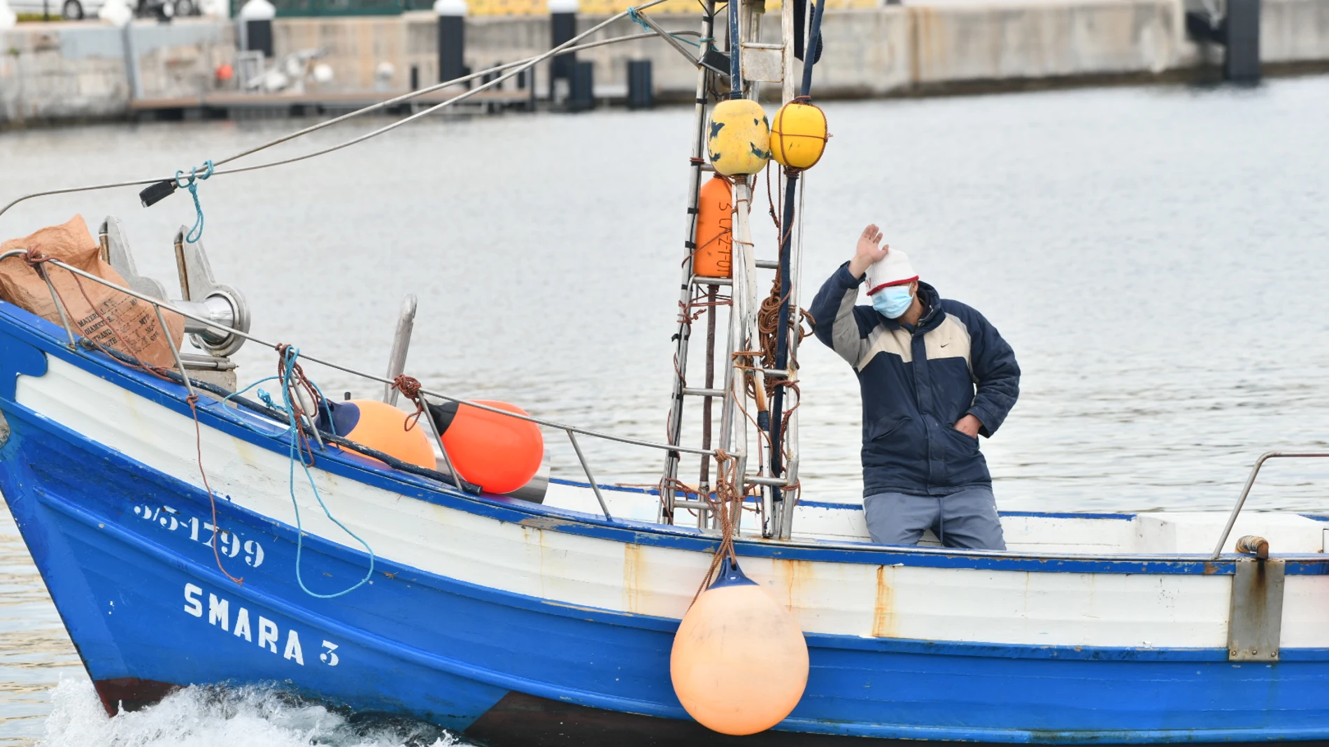 Un hombre saluda al mismo tiempo en que Agentes de Salvamento Marítimo de la Guardia Civil detienen a varios pesqueros marroquíes, a 22 de abril de 2021, en Ceuta