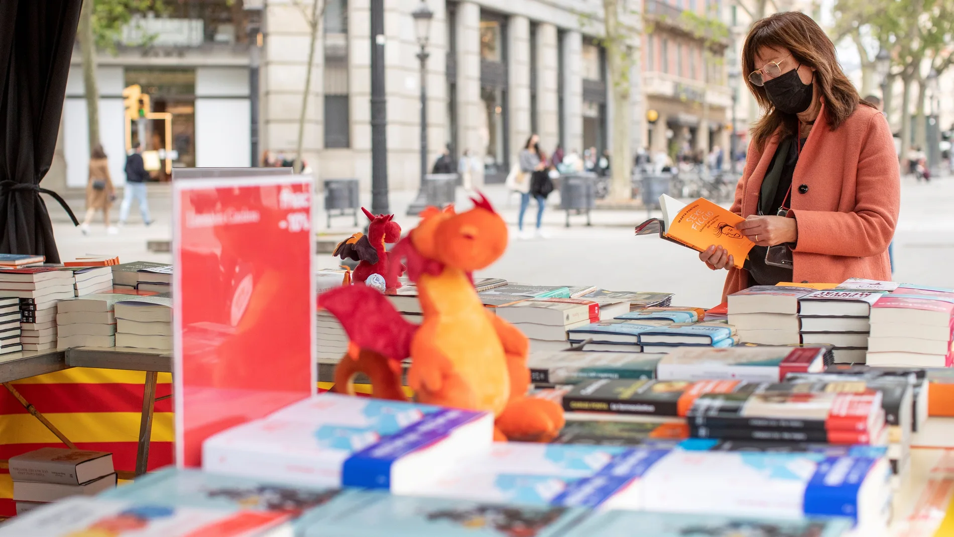 Una cliente busca libros en una conocida librería del centro de Barcelona, ha colocado su puesto de venta en la calle para anticipar y evitar las habituales aglomeraciones en su establecimiento mañana Diada de Sant Jordi, día del libro y de la rosa.