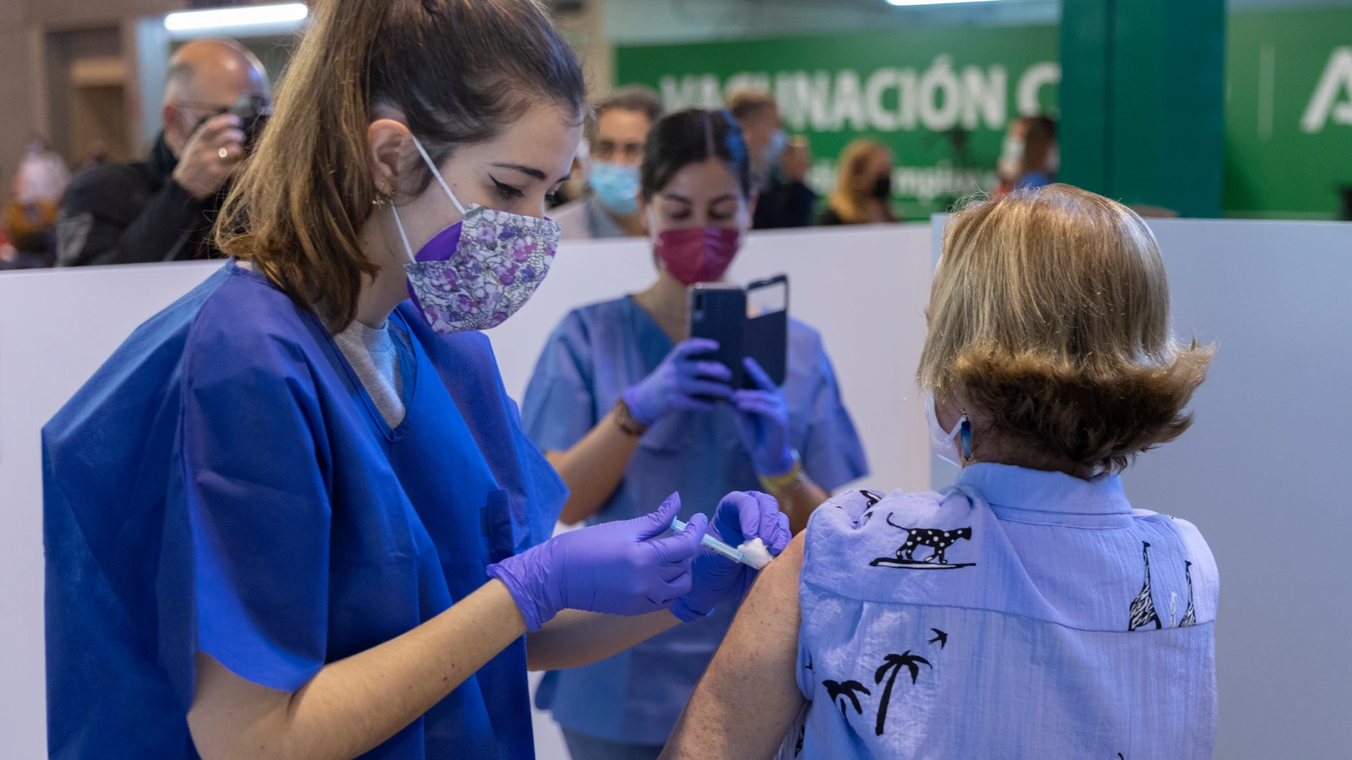 Una sanitaria vacuna a una mujer en la primera jornada de vacunación ante la Covid-19 en el Estadio de La Cartuja de Sevilla