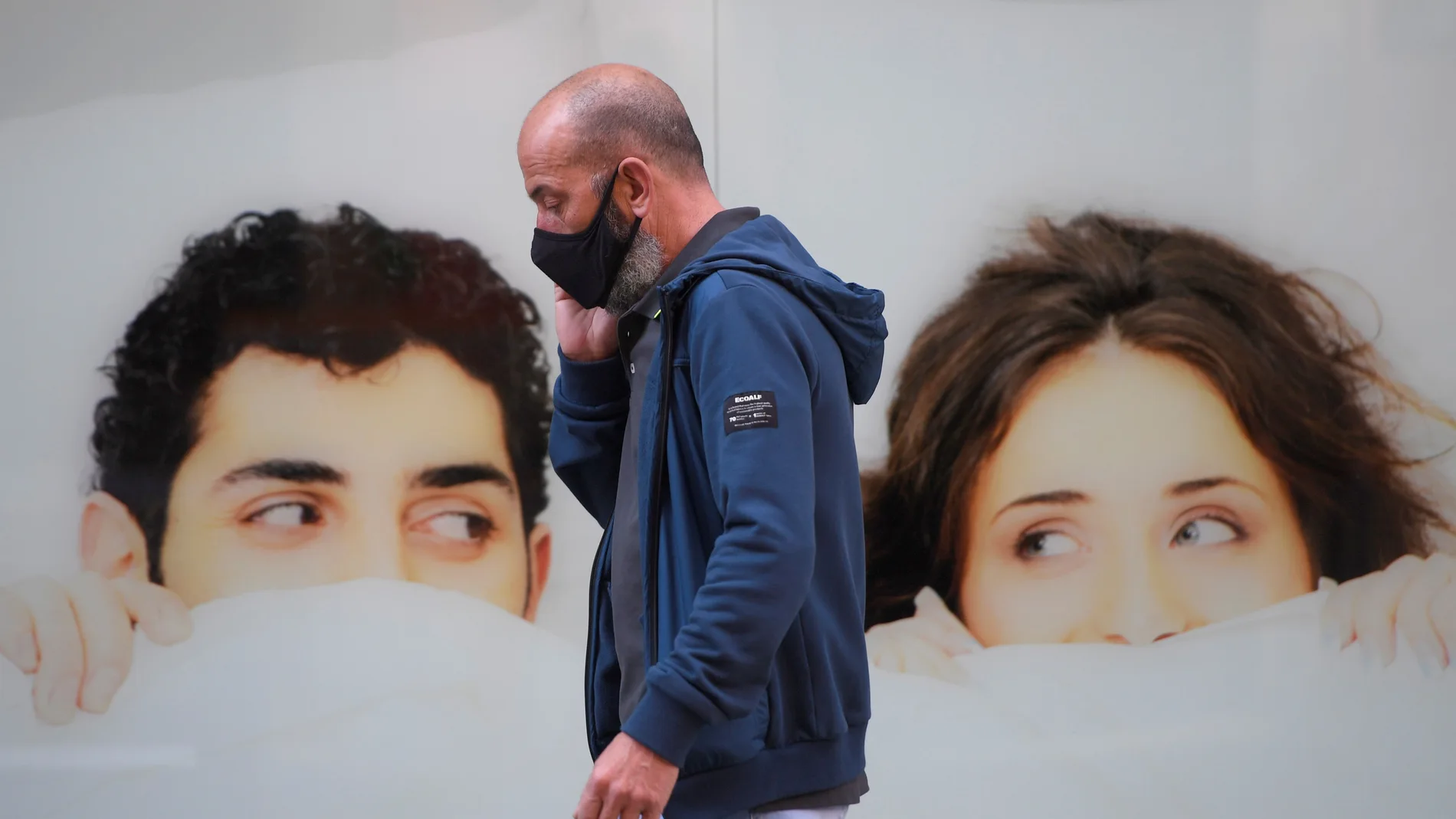 24/04/2021.Un hombre camina con su mascarilla mientras habla por teléfono en una céntrica calle de Gijón