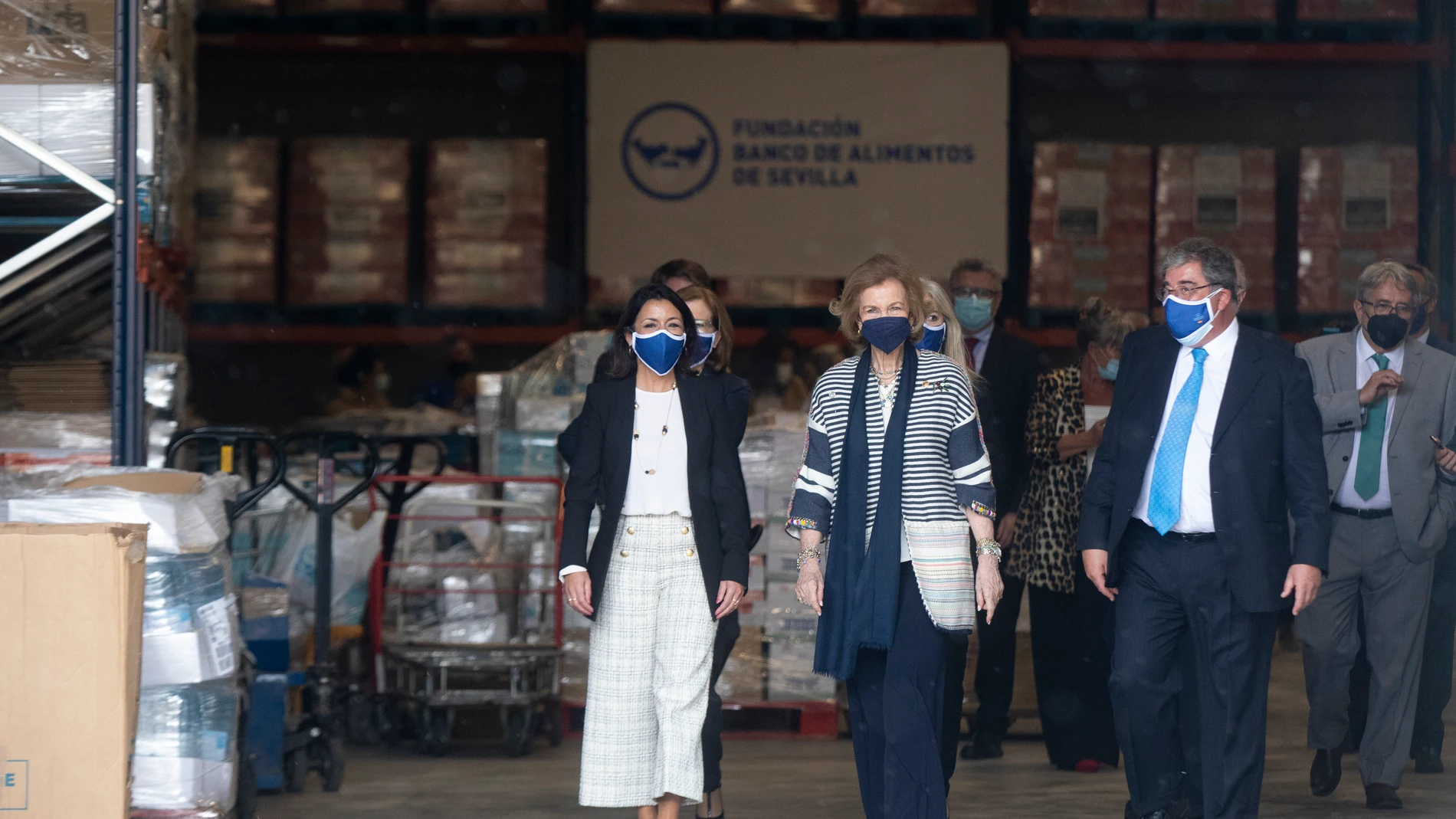 La Reina Sofía (c); junto a la presidenta del Parlamento de Andalucía, Marta Bosquets (i), y el presidente de la fundación, Agustín Vidal-Aragón (d), durante una visita a la Fundación Banco de Alimentos de Sevilla en abril