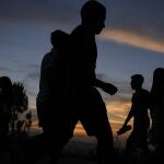People are silhouetted as they walk along the El VolcÃ¡n hill during sunset in the El Hatillo neighborhood of Caracas, Venezuela, Sunday, April 25, 2021. (AP Photo/Matias Delacroix)