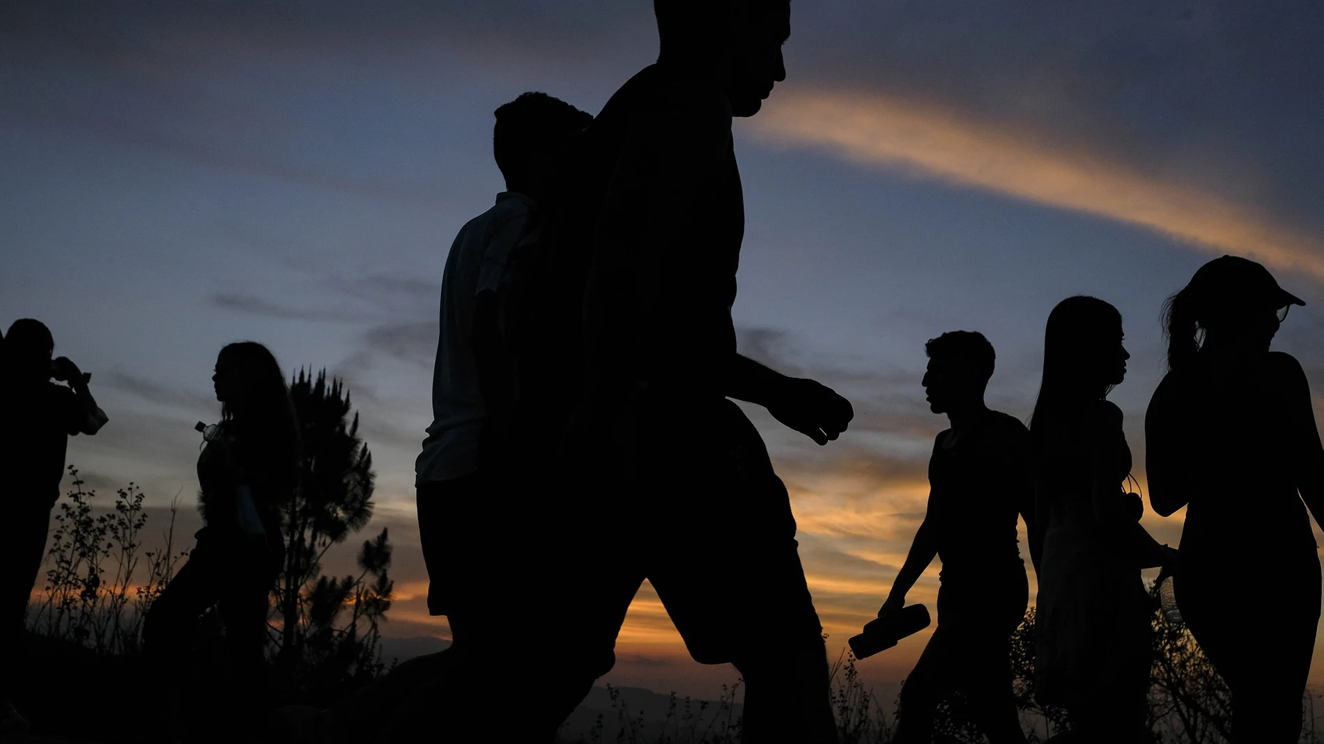 People are silhouetted as they walk along the El VolcÃ¡n hill during sunset in the El Hatillo neighborhood of Caracas, Venezuela, Sunday, April 25, 2021. (AP Photo/Matias Delacroix)