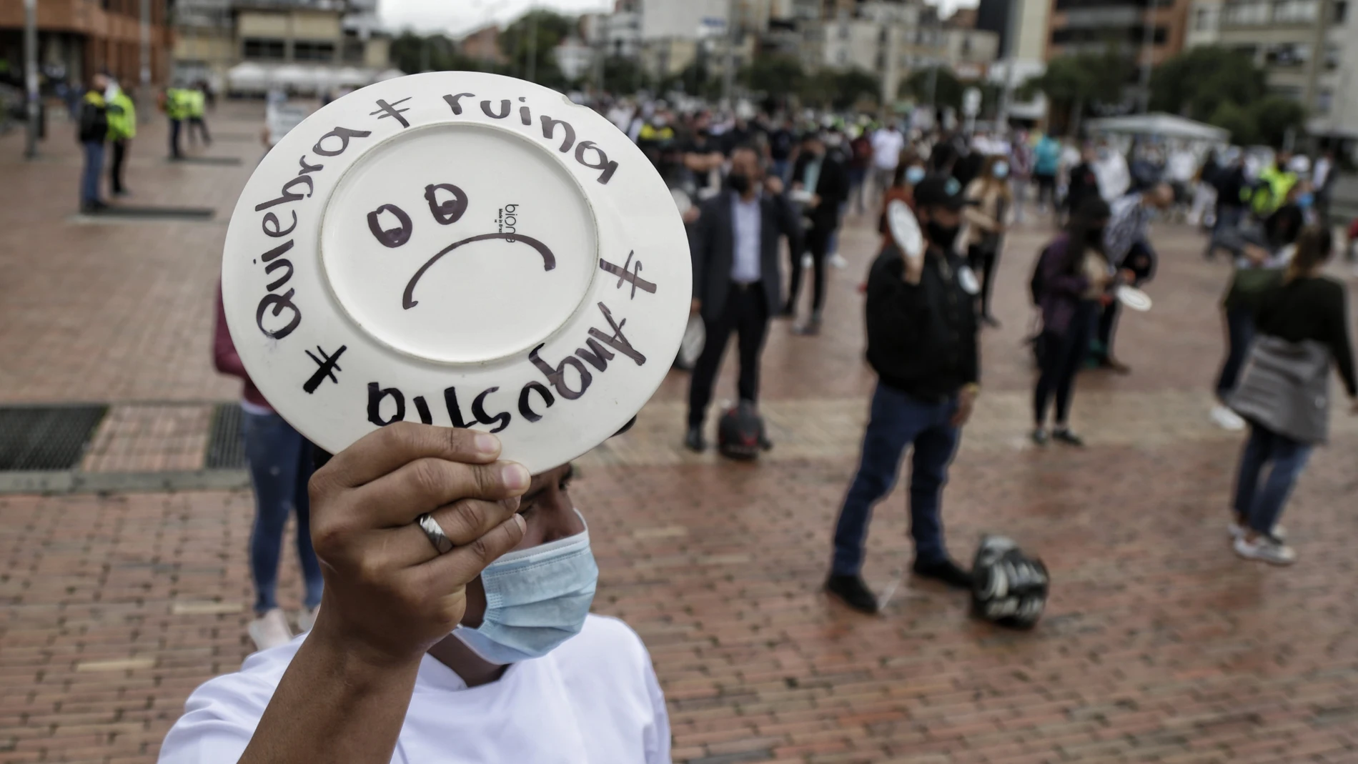 26 April 2021, Colombia, Bogota: A man holds a plate with words reads "Bankruptcy - Ruin", during a protest by restaurant and bar workers to demand support for the sector during the Coronavirus pandemic. Photo: Álvaro Tavera/colprensa/dpa26/04/2021 ONLY FOR USE IN SPAIN