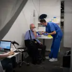 Una sanitaria vacuna a un hombre en el circuito de vacunación de Fira de Barcelona, una prueba piloto para futuras inoculaciones a gran escala cuando lleguen más dosis