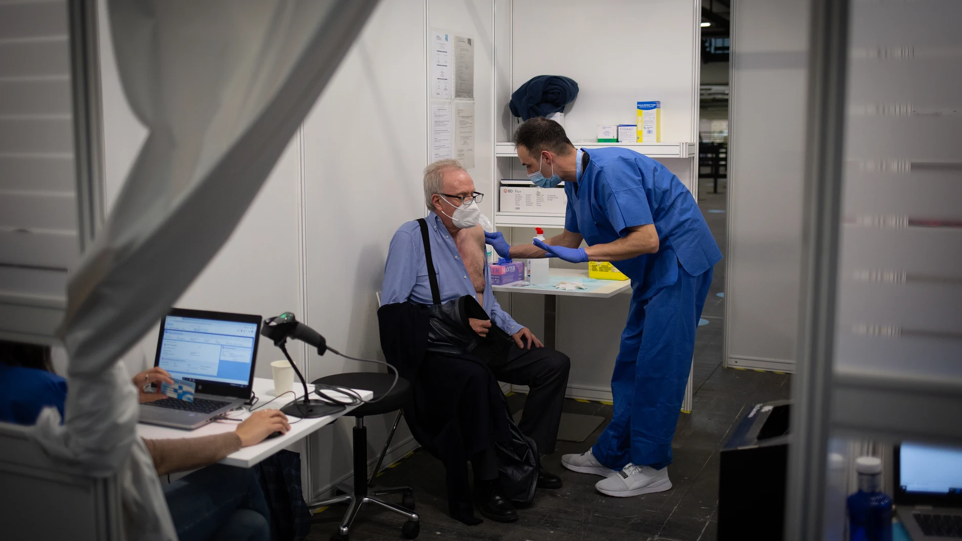 Una sanitaria vacuna a un hombre en el circuito de vacunación de Fira de Barcelona, una prueba piloto para futuras inoculaciones a gran escala cuando lleguen más dosis