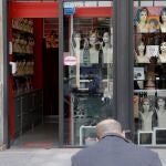 GRAFCVA4219. VALENCIA, 27/04/2021.- Un hombre observa su teléfono móvil, este martes, ante una tienda de pelucas y postizos en el centro de València. EFE/Manuel Bruque