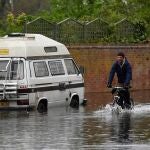 A Un hombre pedalea en una calle de Londres donde el río Támesis se ha desbordado