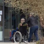 Una mujer pasea junto a un anciano en silla de ruedas