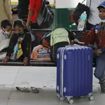 Hijos de trabajadores migrantes esperan transporte en una estación de autobuses durante un cierre en Nueva Delhi