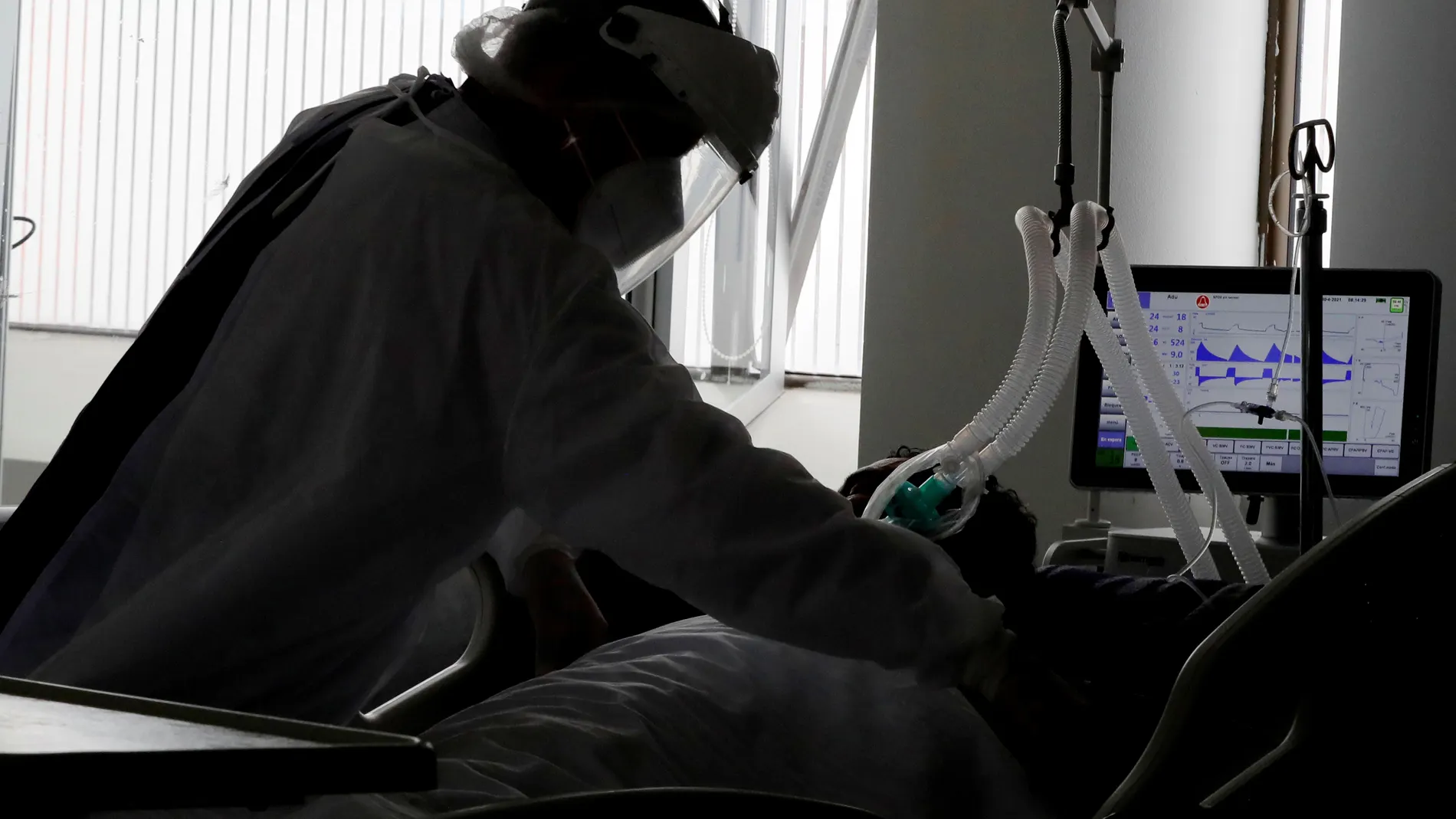 Una empleada de la salud atiende a un paciente en una unidad de cuidados intensivos para enfermos de Covid-19