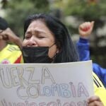 A woman cries as she sings the Colombian national anthem, during a demonstration outside Colombia's embassy in Quito, Ecuador, Tuesday, May 4, 2021. The demonstration is in support of the protests going on in Colombia over the tax reform proposal by the government that has left several dead in that country. (AP Photo/Dolores Ochoa)