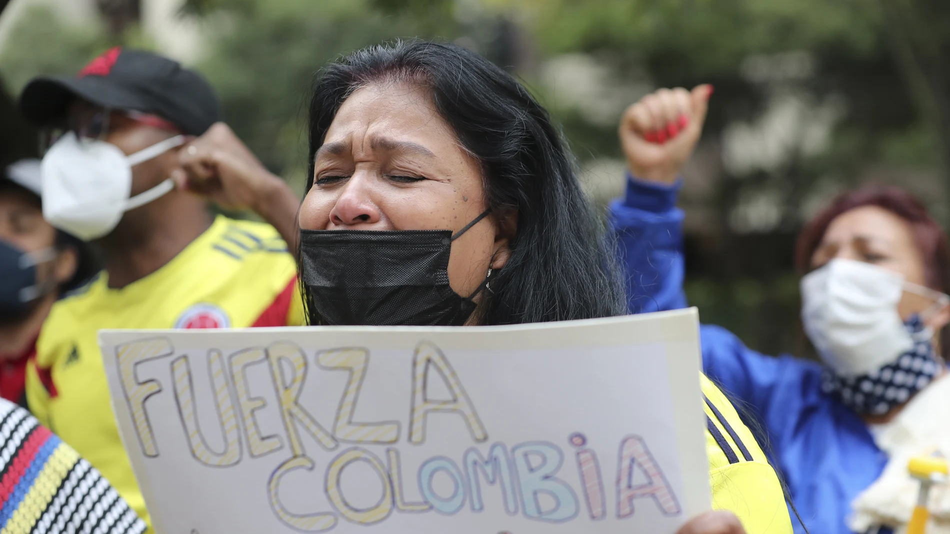 A woman cries as she sings the Colombian national anthem, during a demonstration outside Colombia's embassy in Quito, Ecuador, Tuesday, May 4, 2021. The demonstration is in support of the protests going on in Colombia over the tax reform proposal by the government that has left several dead in that country. (AP Photo/Dolores Ochoa)