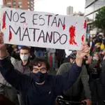 Un manifestante sujeta una pancarta con el mensaje &quot;Nos están matando&quot; en Bogotá (Colombia), el 4 de mayo de 2021