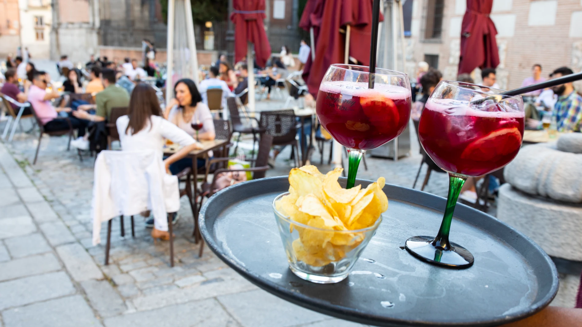 Imagen de un camarero llevando dos tintos de verano a una mesa de una terraza en Madrid.