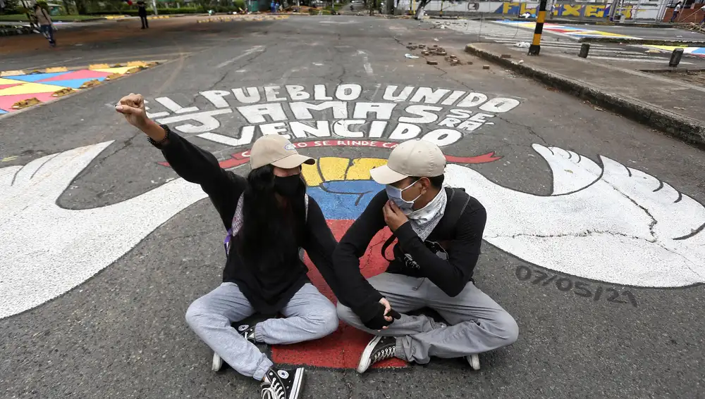 Dos personas se manifiestan durante un bloqueo en el marco del Paro Nacional en el sur de Cali (Colombia