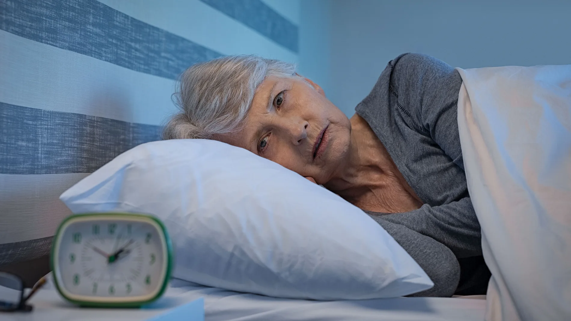 Mujer mayor preocupada en la cama por la noche que sufre de insomnio