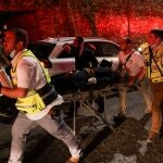 Trabajadores de rescate transportan en camilla a personas heridas fuera de una sinagoga donde una tribuna se derrumbó durante una celebración religiosa en Givat Zeev, en Cisjordania