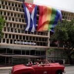 People pass in a vintage car in front of a rainbow flag hanging beside a Cuban flag at the Health Ministry building in Havana, Cuba, May 17, 2021. REUTERS/Alexandre Meneghini