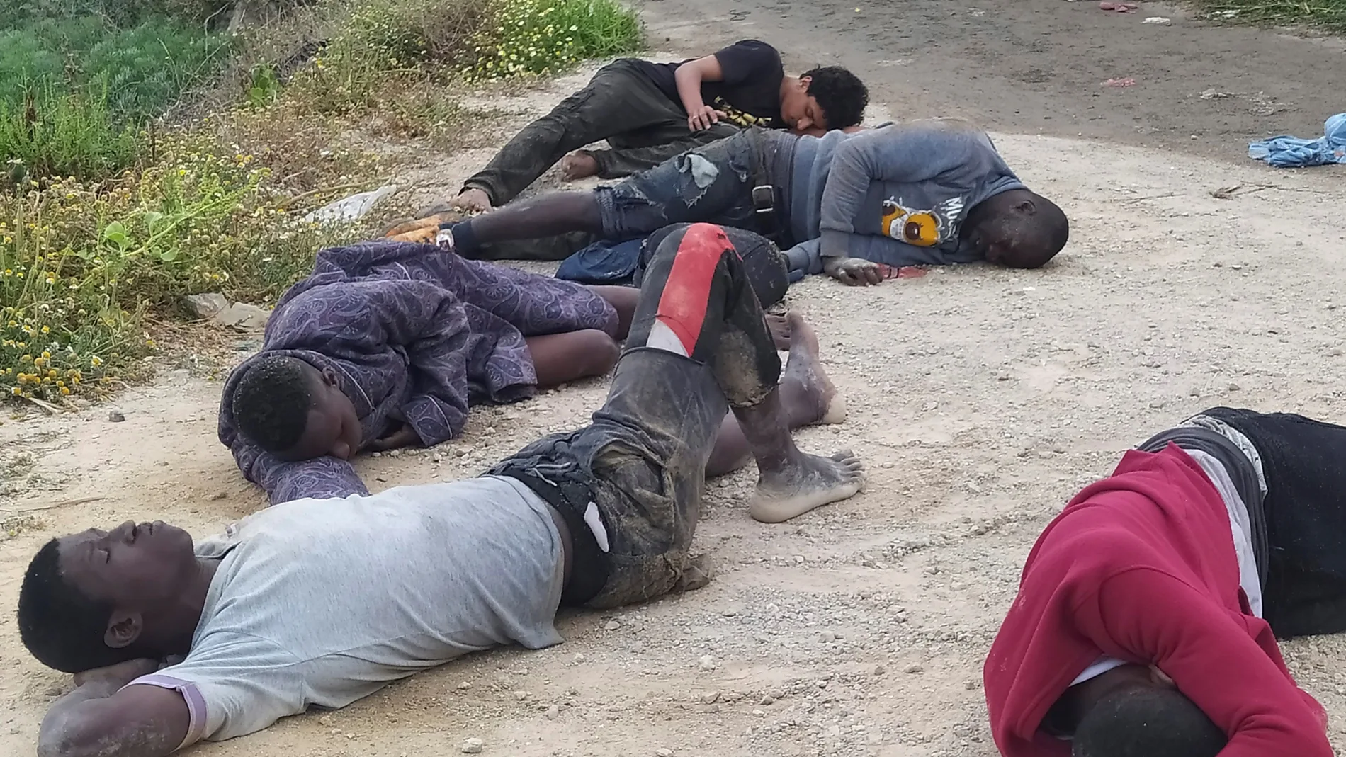 Un grupo de inmigrantes descansa tras su llegada este martes a uno de los espigones fronterizos de Ceuta