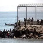 Soldados del Ejército de Tierra observan cómo un grupo de inmigrantes escalan las rocas del espigón de la playa fronteriza de El Tarajal de Ceuta, en mayo pasado