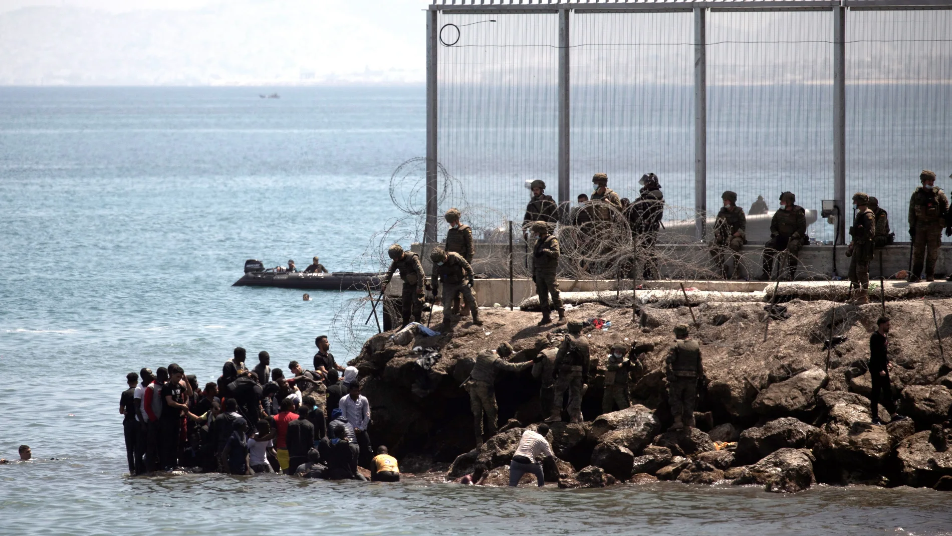 Soldados del Ejército de Tierra observan cómo un grupo de inmigrantes escalan las rocas del espigón de la playa fronteriza de El Tarajal de Ceuta, en mayo pasado