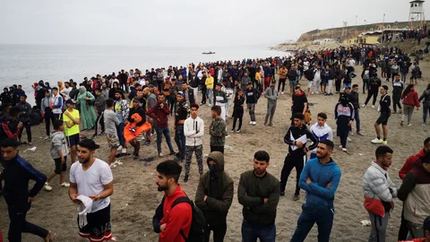 Cientos de personas esperan en la playa de la localidad de Fnideq (Castillejos) para cruzar los espigones de Ceuta en una avalancha de inmigrantes sin precedentes en España