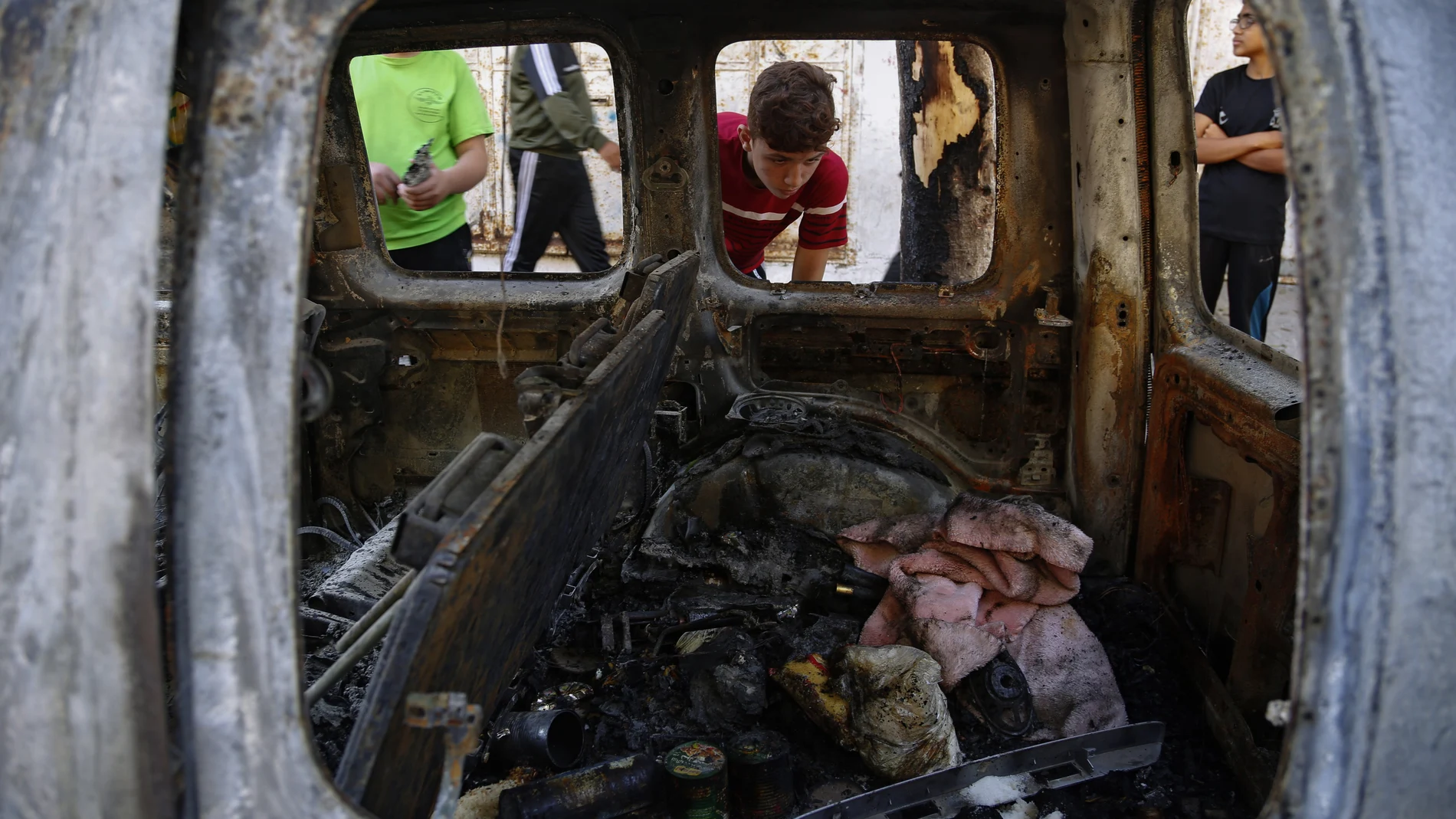 Niños palestinos observan el interior de un coche alcanzado por una bomba israelí en Gaza