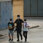 Agentes de la Policía Nacional acompañan a menores marroquíes a las naves acondicionadas anexas a la frontera del Tarajal en Ceuta a 20 de mayo de 2021.