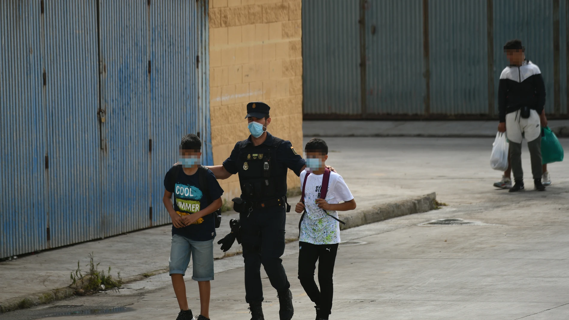 Agentes de la Policía Nacional acompañan a menores marroquíes a las naves acondicionadas anexas a la frontera del Tarajal en Ceuta a 20 de mayo de 2021.