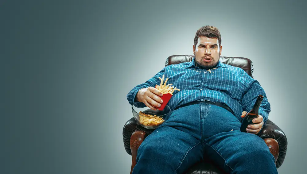Persona obesa comiendo comida basura