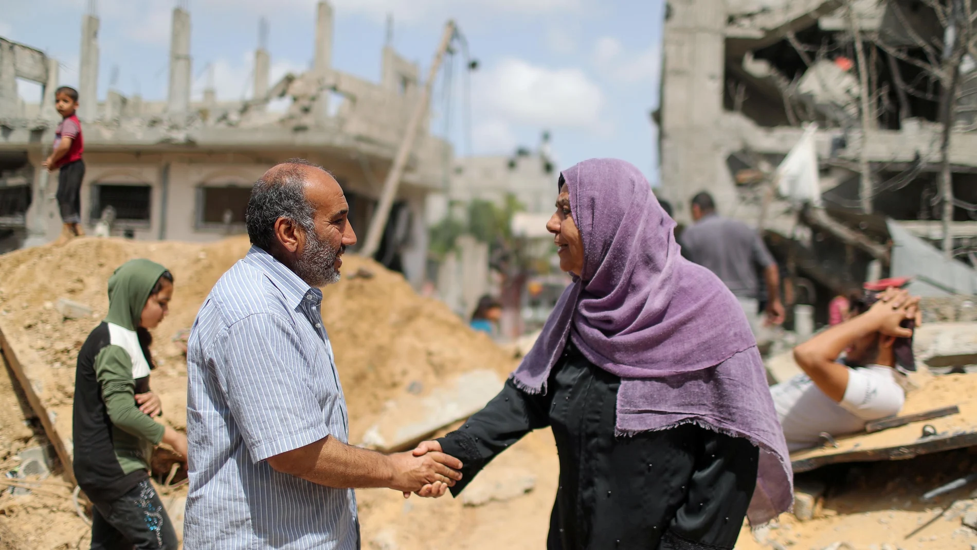 Dos palestinos se dan la mano después de regresar a sus casas destruidas tras la tregua entre Israel y Hamas, en Beit Hanoun, en el norte de la Franja de Gaza, hoy
