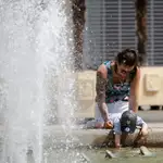 Una joven y un niño se refrescan en una fuente del centro de la ciudad