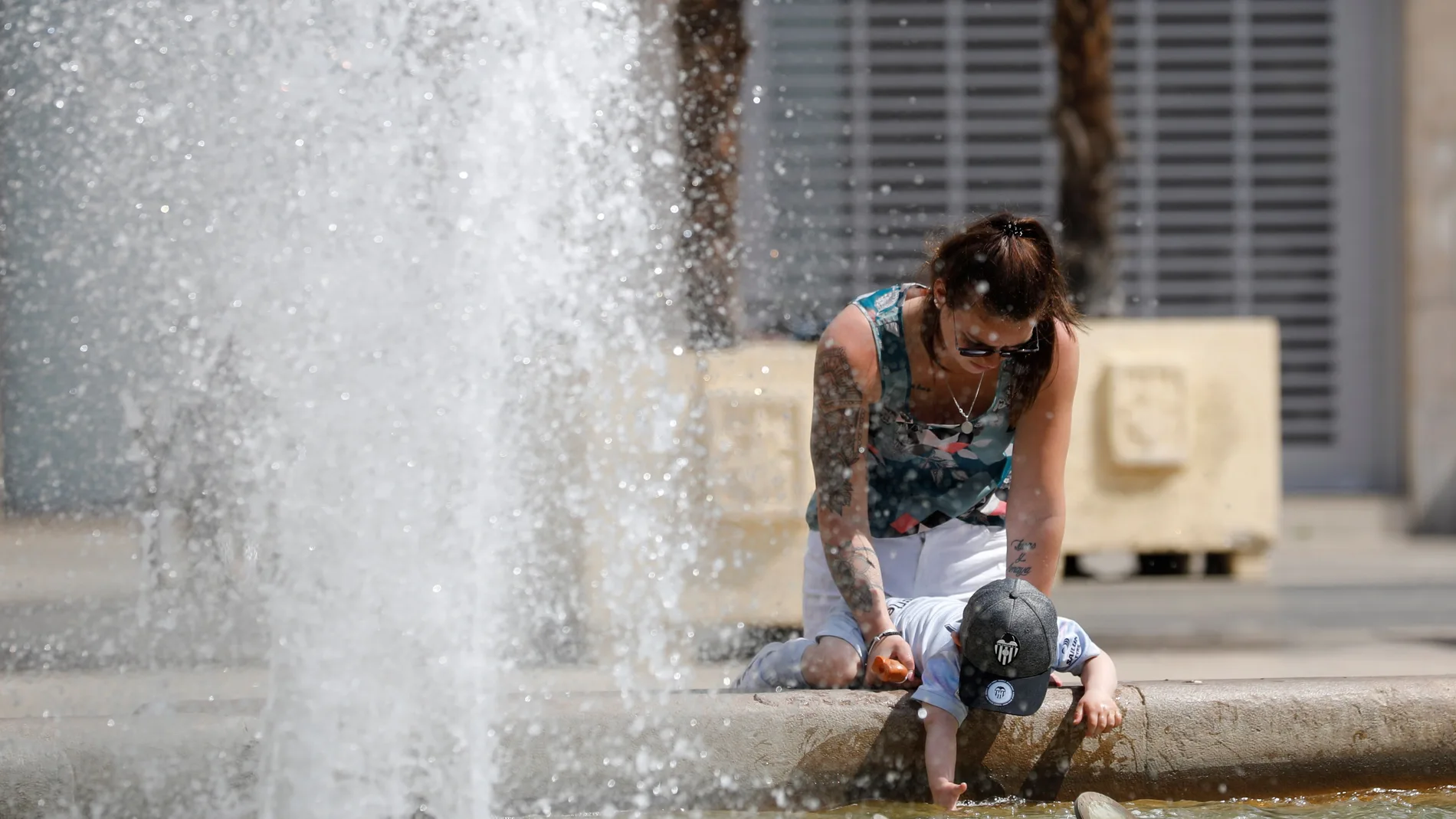 Una joven y un niño se refrescan en una fuente del centro de la ciudad