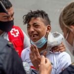 Un menor que tenía miedo de ser devuelto a Marruecos llora ante un voluntario de Cruz Roja y un efectivo de la Policía Nacional