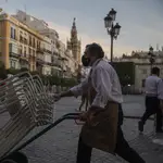 Un camarero recoge el mobiliario de la terraza de un bar en Sevilla