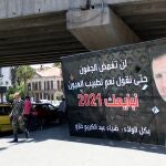 Varios peatones pasa junto a un cartel electoral que muestra al presidente sirio, Bachar Al Assad, en Damasco