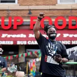 Un afroamericano levanta el puño a las puertas establecimiento Cup Food donde murió hace un año George Floyd en Mineápolis