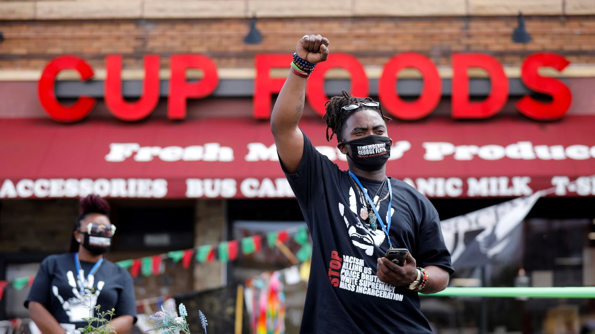 Un afroamericano levanta el puño a las puertas establecimiento Cup Food donde murió hace un año George Floyd en Mineápolis