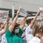 Varias personas de Juntas de Personal de departamentos de Salud con carteles, durante una concentración contra el cese de los contratos refuerzo Covid, en la puerta del Hospital de La Fe, en Valencia