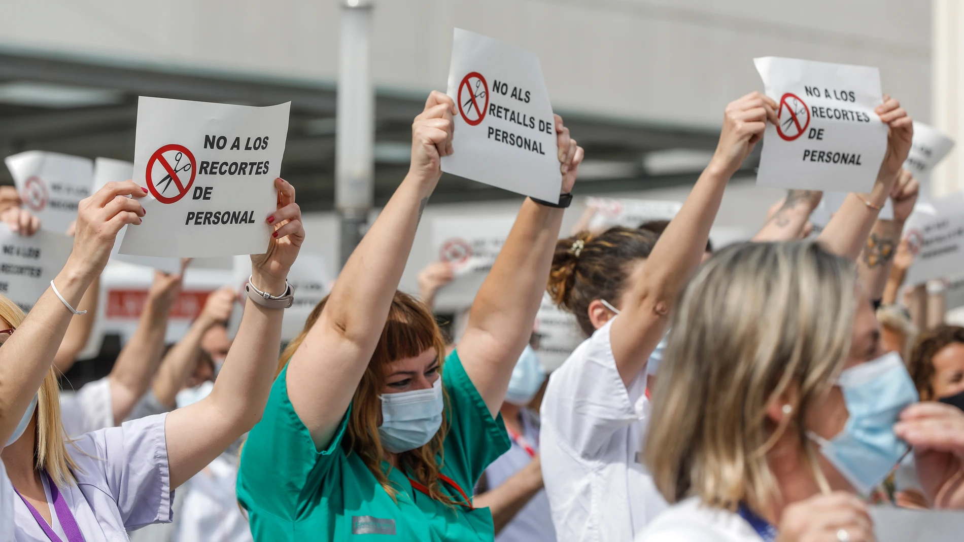 Varias personas de Juntas de Personal de departamentos de Salud con carteles, durante una concentración contra el cese de los contratos refuerzo Covid, en la puerta del Hospital de La Fe, en Valencia