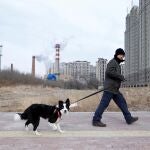 Un hombre camina con su perro en la ciudad china de Harbin