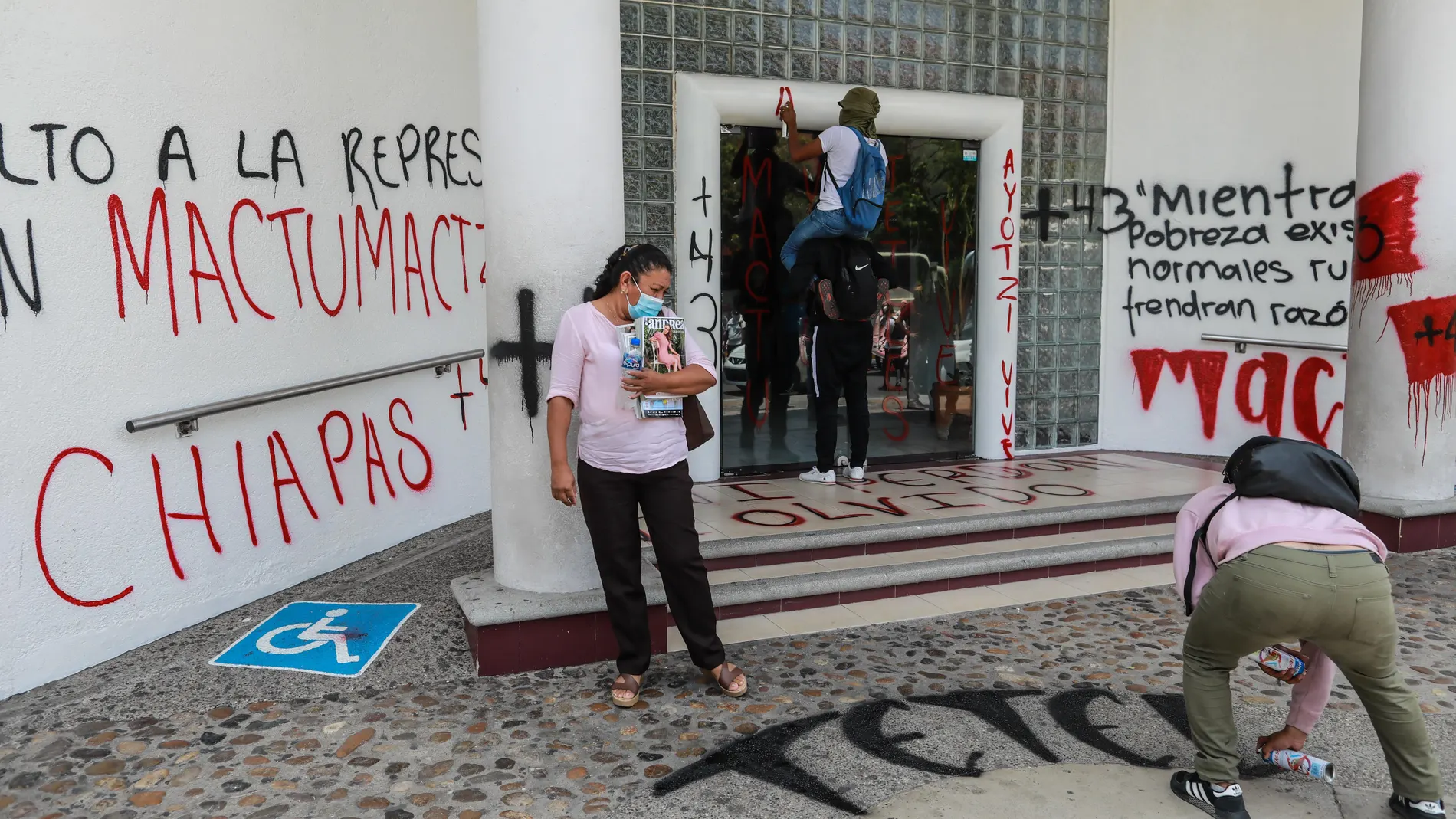 Varias personas pintan mensajes sobre las paredes y el piso del Palacio Federal durante unas protestas recientes en Acapulco, estado de Guerrero (México)